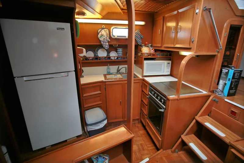 Slide: The Image of 1987 Jefferson 42 Sundeck Motor Yacht kitchen with fridge, stove, microwave, and wooden cabinetry. - 34