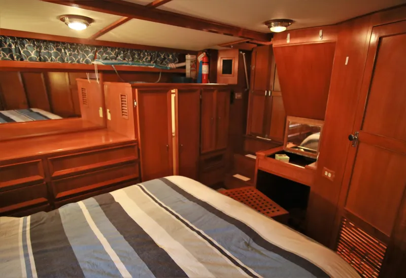 Slide: The Image of 1987 Jefferson 42 Sundeck Motor Yacht bedroom with wooden cabinetry and striped bedding. - 37
