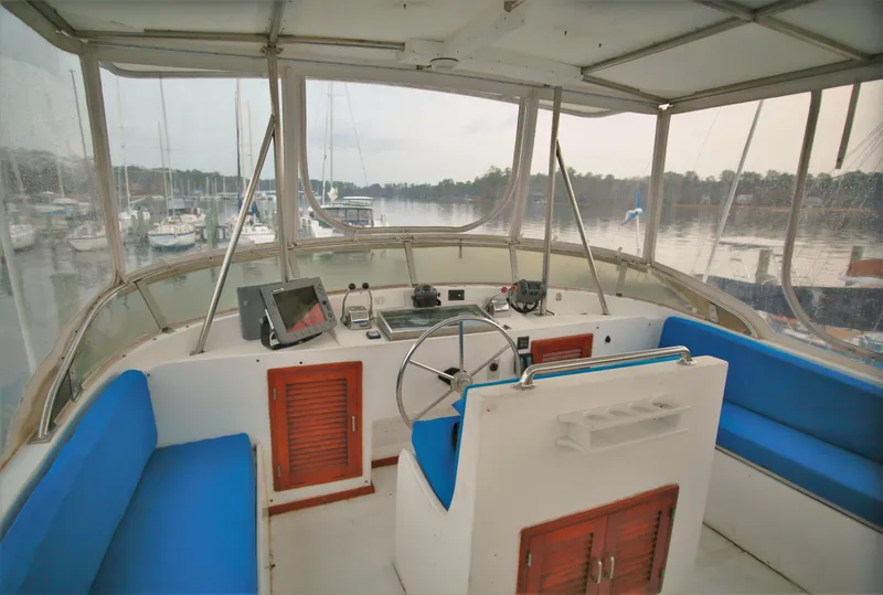 Slide: The Image of 1987 Jefferson 42 Sundeck Motor Yacht helm station with blue seating and marina view. - 4