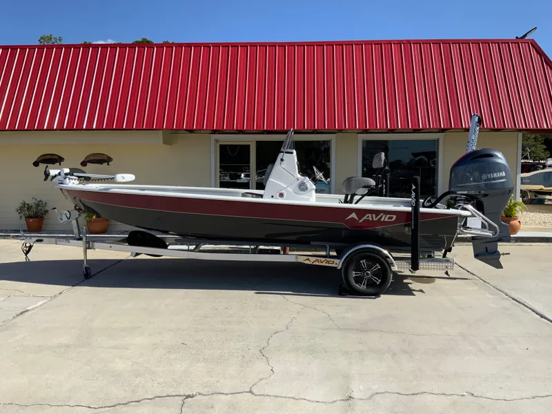The Image of 2023 Avid 21 Mag boat on trailer, parked outside a building with a red roof. - 1
