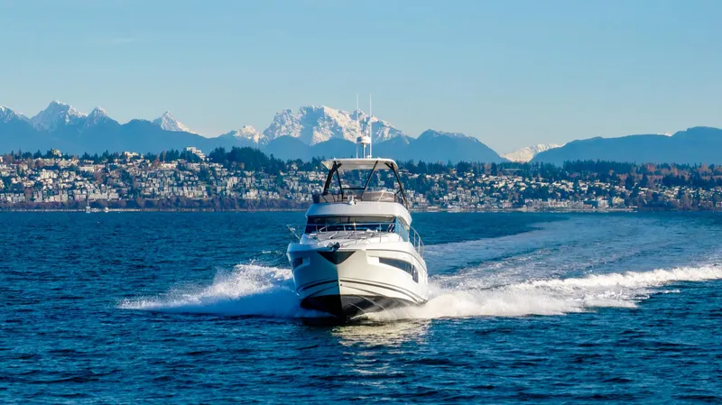Slide: The Image of 2024 Prestige 460 yacht cruising on a scenic lake with mountains in the background. - 4