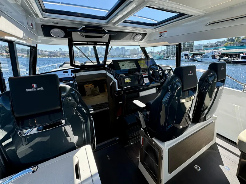 Slide: The Image of 2024 Wellcraft 355 boat interior with modern dashboard and seating, overlooking marina. - 17