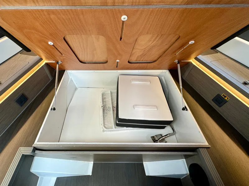 Slide: The Image of 2024 Wellcraft 355 storage compartment with wooden lid and organized interior. - 21