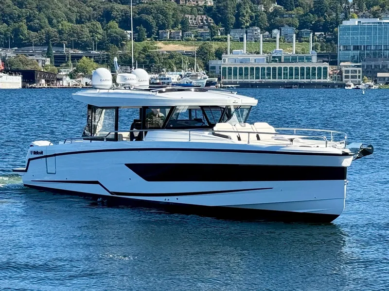 Slide: The Image of 2024 Wellcraft 355 boat cruising on a scenic lake with city backdrop. - 4