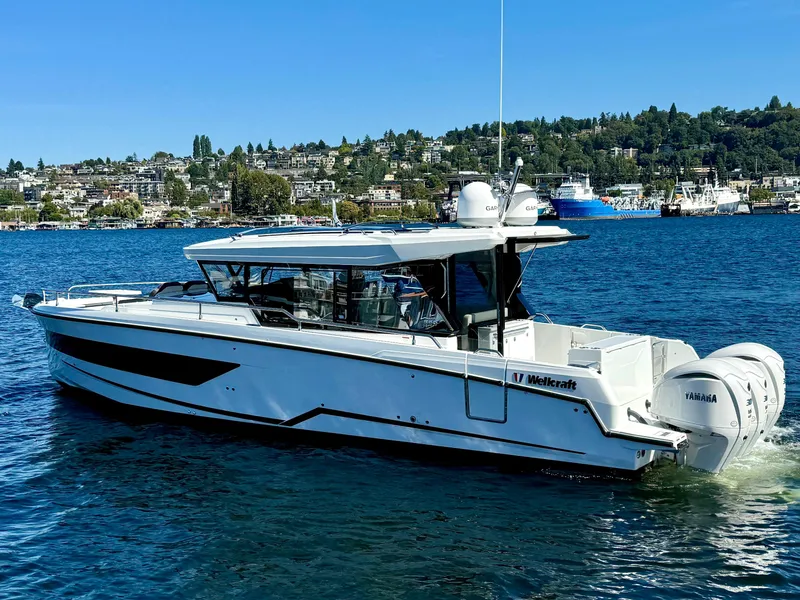 Slide: The Image of 2024 Wellcraft 355 boat on a scenic lake with a city backdrop. - 9