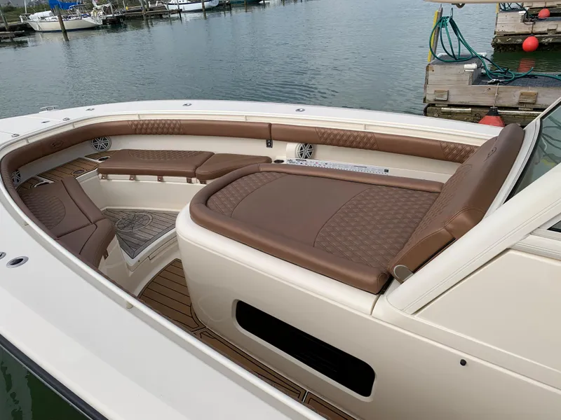 Slide: The Image of 2018 Scout 350 LXF boat with brown leather seating, docked by the water. - 19