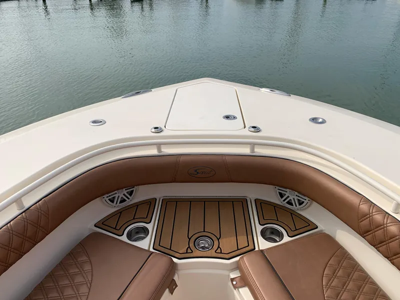 Slide: The Image of 2018 Scout 350 LXF boat interior with tan seating and wood accents on calm water. - 48
