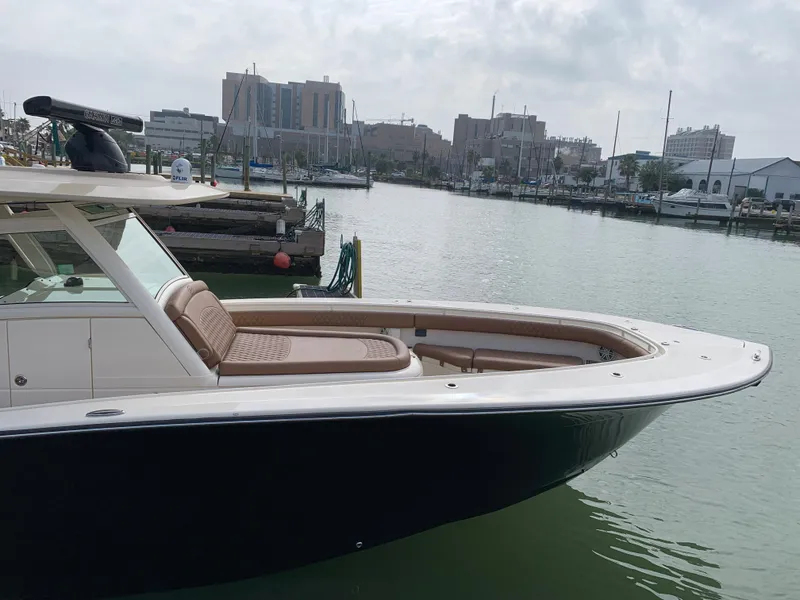 Slide: The Image of 2018 Scout 350 LXF boat docked in a marina with cityscape background. - 7