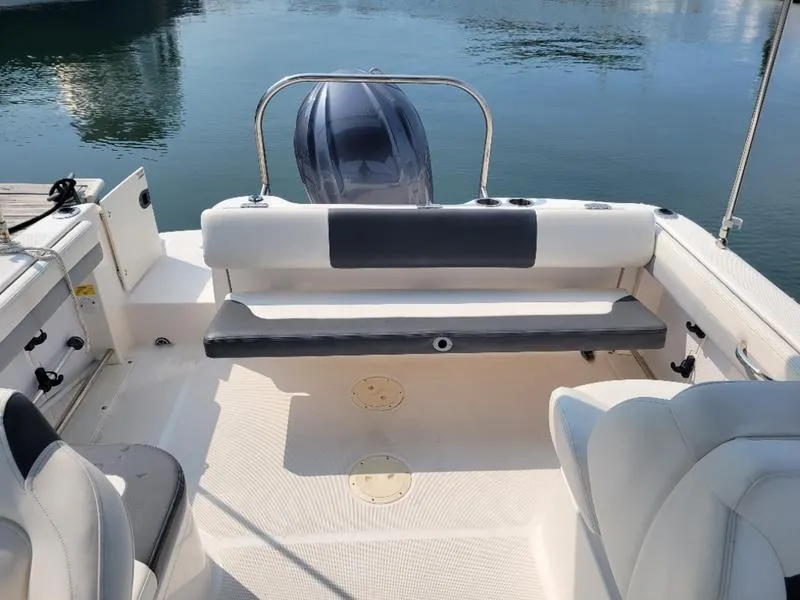 Slide: The Image of 2023 Robalo 227 DC boat interior with seating and motor, docked on calm water. - 13