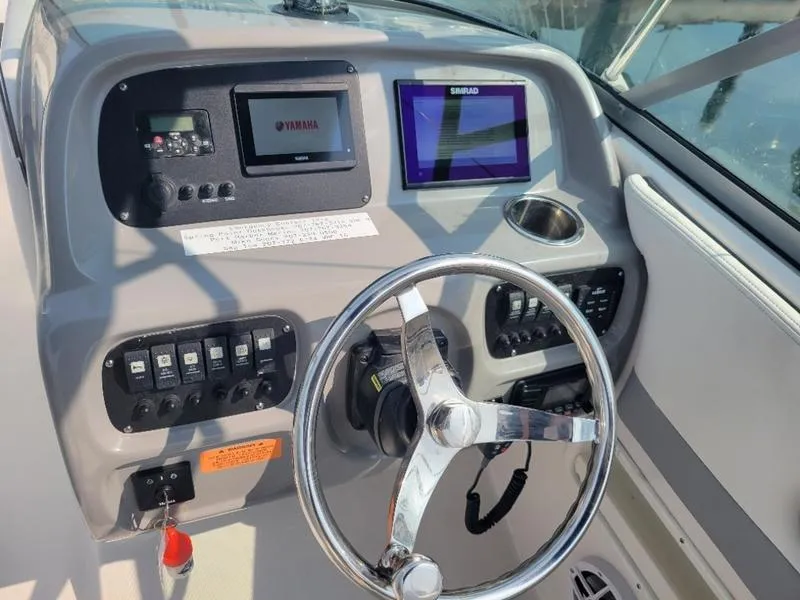 Slide: The Image of 2023 Robalo 227 DC boat dashboard with steering wheel and electronic displays. - 16