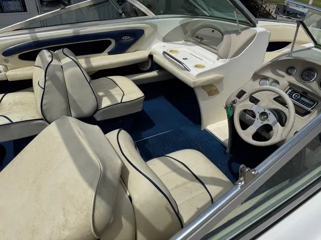 Slide: The Image of Interior of a 1997 Sea Ray 210 Signature boat with beige seating and blue carpet. - 8