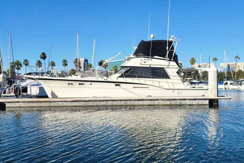 The Image of 1978 Hatteras Sportfish yacht docked in a marina under clear blue skies. - 0