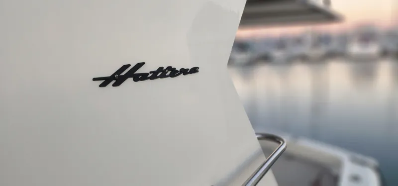 Slide: The Image of 1978 Hatteras Sportfish boat with logo, docked at marina during sunset. - 11