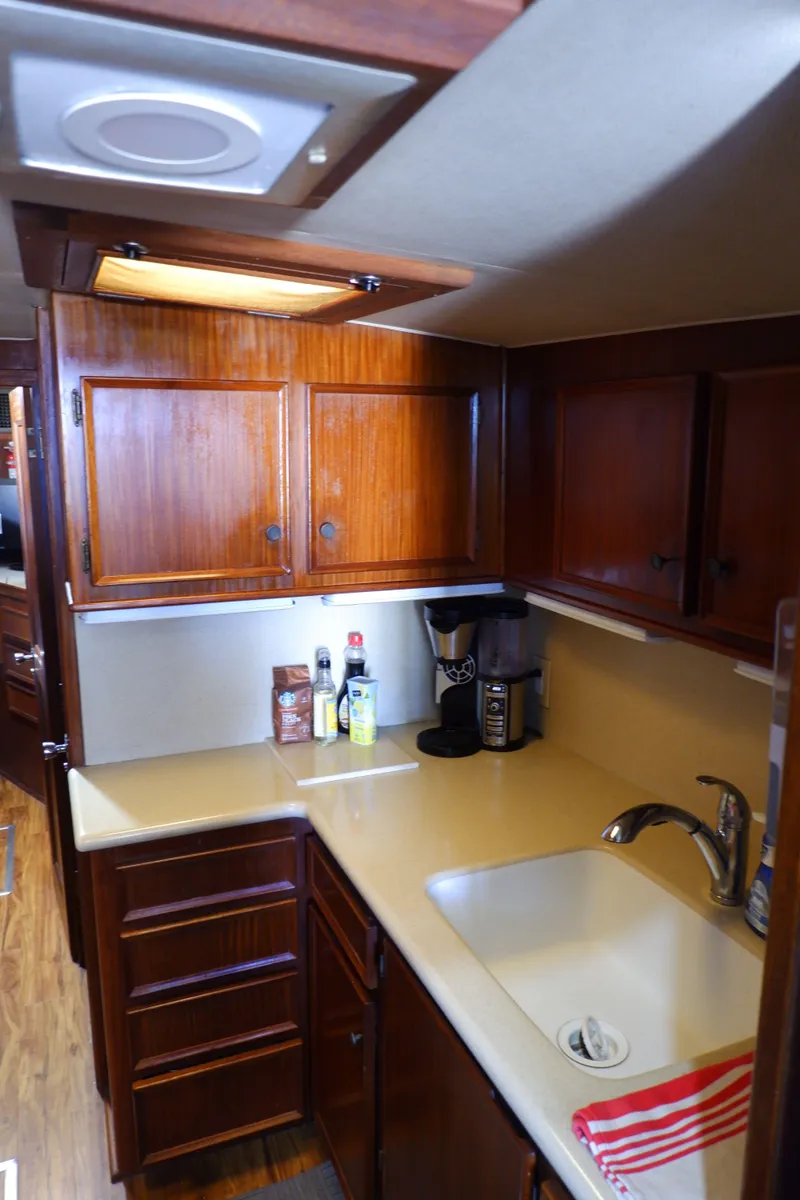 Slide: The Image of 1978 Hatteras Sportfish kitchen with wooden cabinets, sink, and countertop appliances. - 19