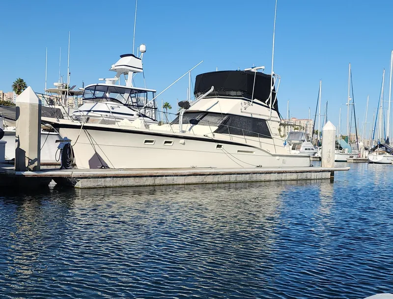 Slide: The Image of 1978 Hatteras Sportfish yacht docked in a marina under clear blue skies. - 2