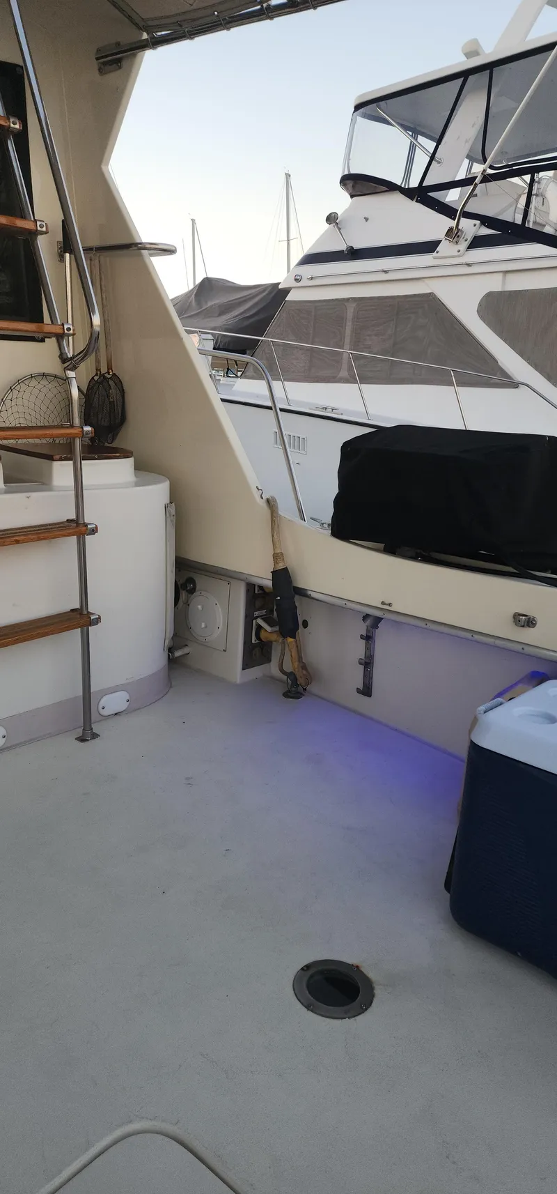 Slide: The Image of 1978 Hatteras Sportfish boat deck with visible stairs and adjacent docked vessel. - 20