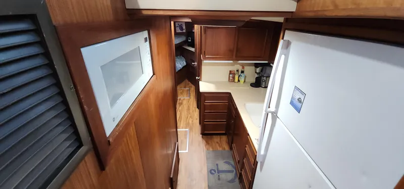 Slide: The Image of 1978 Hatteras Sportfish interior kitchen with wooden cabinets and white appliances. - 35