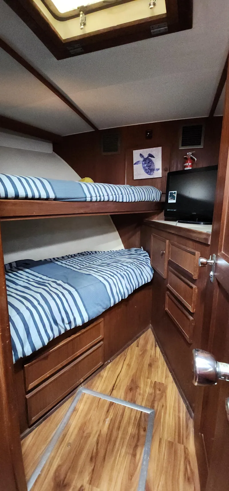 Slide: The Image of 1978 Hatteras Sportfish cabin with bunk beds, wood paneling, and striped bedding. - 40
