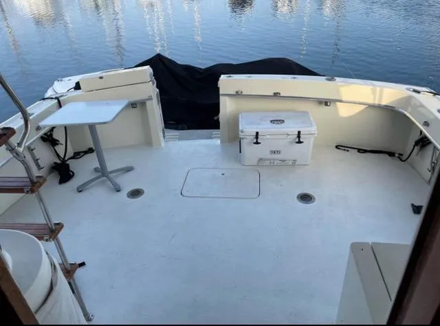 Slide: The Image of 1978 Hatteras Sportfish boat deck with table and cooler, docked by calm water. - 5