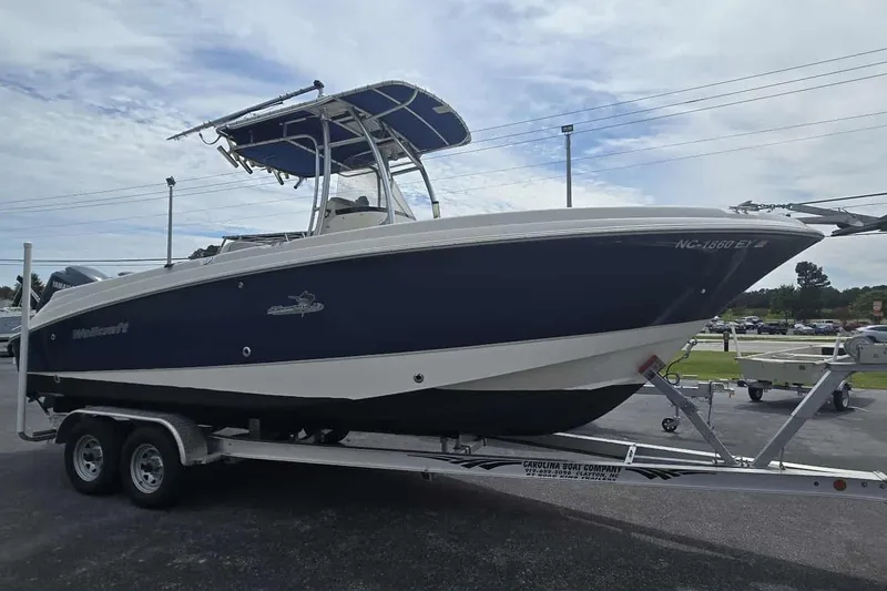 Slide: The Image of 2004 Wellcraft 252 Fisherman boat on trailer, blue and white hull, parked outdoors. - 2