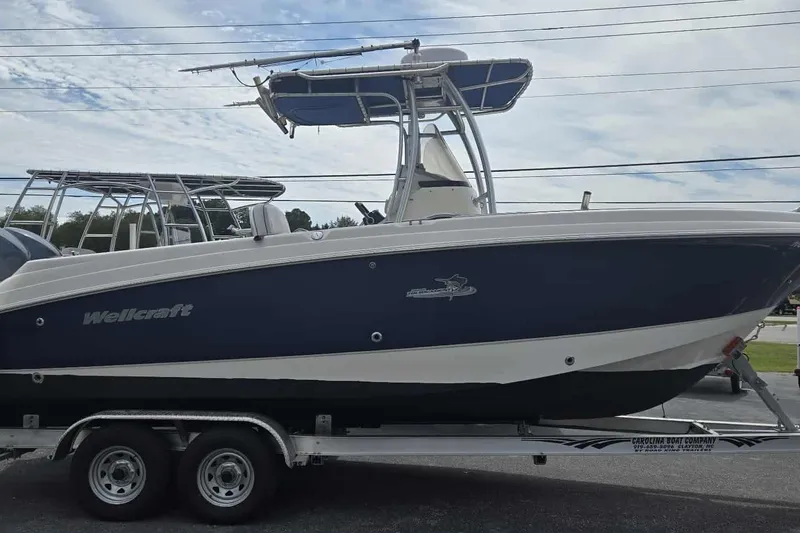 Slide: The Image of 2004 Wellcraft 252 Fisherman boat on trailer, blue and white design, clear sky background. - 3