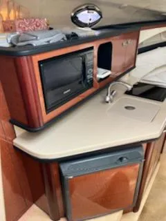 Slide: The Image of 2005 Sea Ray 270 Amberjack boat interior kitchen with microwave, sink, and mini-fridge. - 14