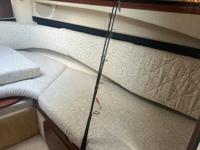 Slide: The Image of 2005 Sea Ray 270 Amberjack cabin interior with cushioned seating and fishing rod. - 33