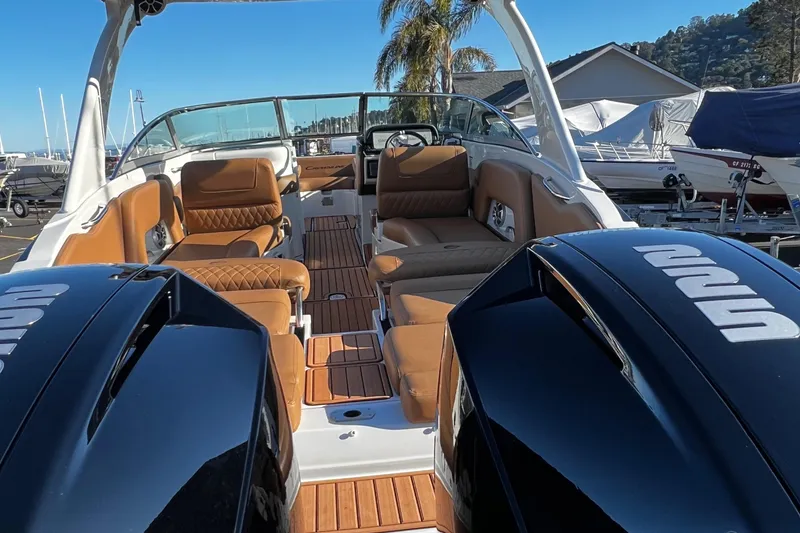 Slide: The Image of 2023 Crownline E305XS boat interior with tan seating and dual outboard engines. - 3