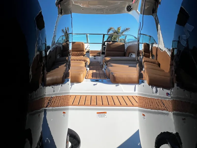 Slide: The Image of 2023 Crownline E305XS boat interior with tan seating and wooden deck. - 5