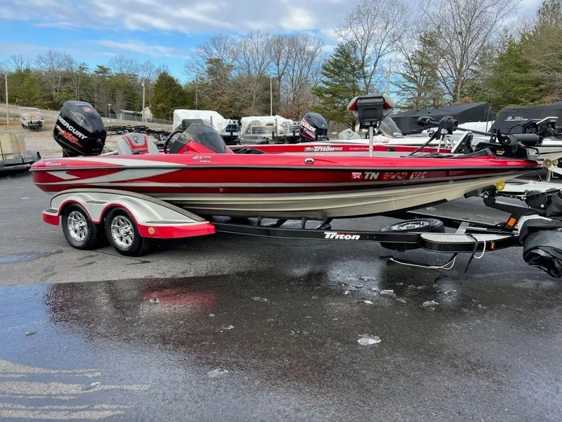 The Image of 2016 Triton 21 TrX bass boat on trailer, red and white, parked outdoors. - 1