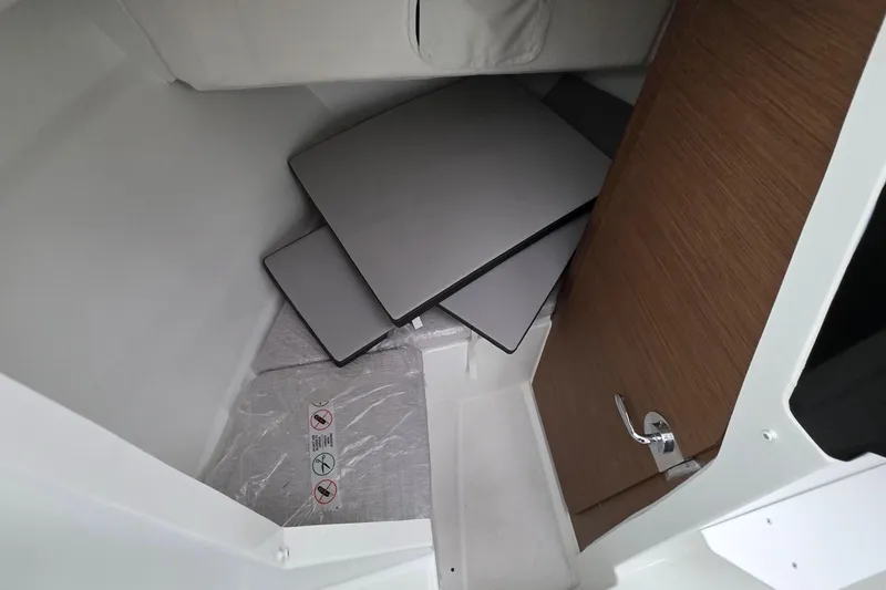 Slide: The Image of 2023 Jeanneau NC 695 Sport Serie 2 cabin interior with stacked cushions and wooden door. - 19