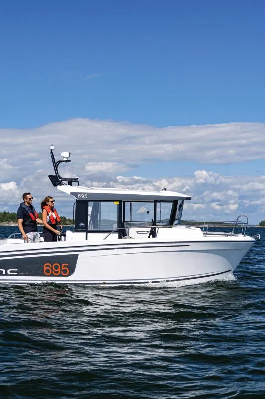Slide: The Image of 2023 Jeanneau NC 695 Sport S2 boat cruising near rocky shoreline. - 3