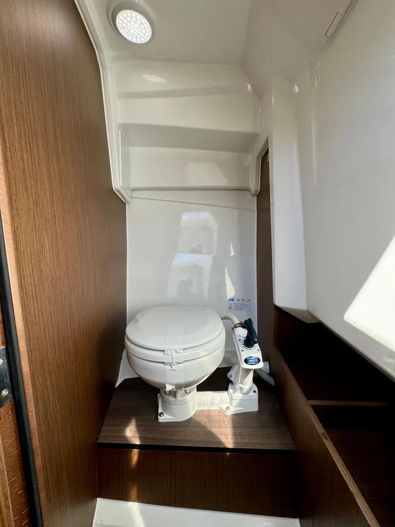 Slide: The Image of 2024 Jeanneau Leader 7.5 WA boat interior with modern toilet and wooden accents. - 19