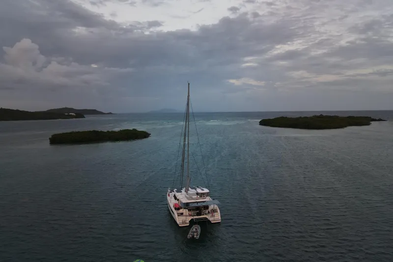 Slide: The Image of Sailing catamaran Leopard 50, 2023 model, anchored between lush islands under cloudy skies. - 3
