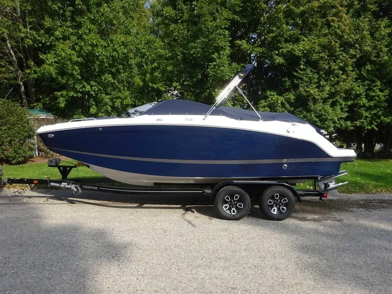 Slide: The Image of 2023 Four Winns HD3 boat on a trailer, parked on a road with trees in the background. - 20