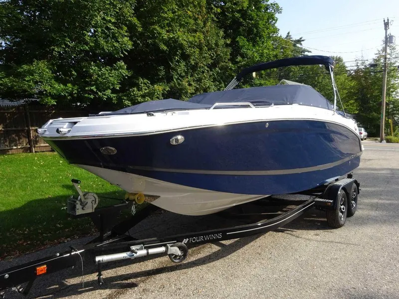 Slide: The Image of 2023 Four Winns HD3 boat on a trailer, parked outdoors. - 23