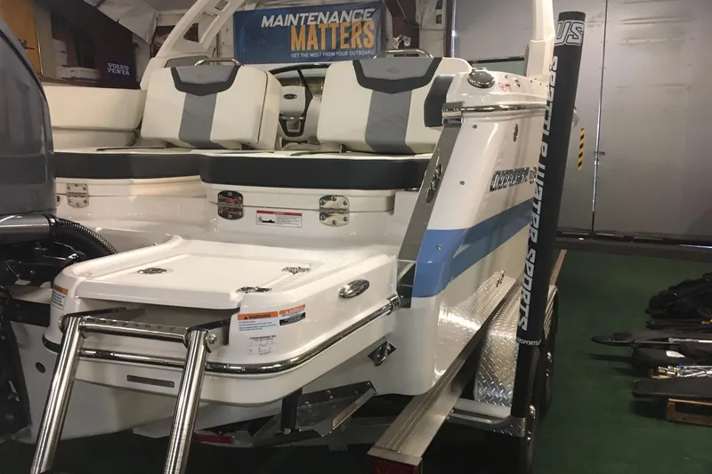 Slide: The Image of 2023 Chaparral 250 OSX boat with swim platform and seating, showcased indoors. - 12