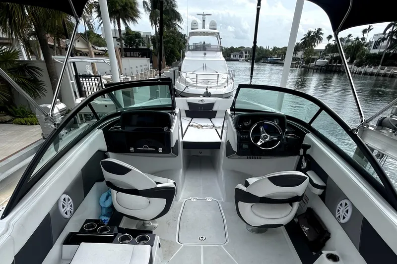 Slide: The Image of 2022 Monterey M225 boat interior with steering wheel and seating, docked by a canal. - 11