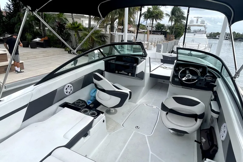 Slide: The Image of 2022 Monterey M225 boat interior with modern seating and steering wheel, docked by a waterfront. - 12