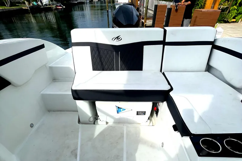 Slide: The Image of 2022 Monterey M225 boat interior with white and black seating, docked by the water. - 18