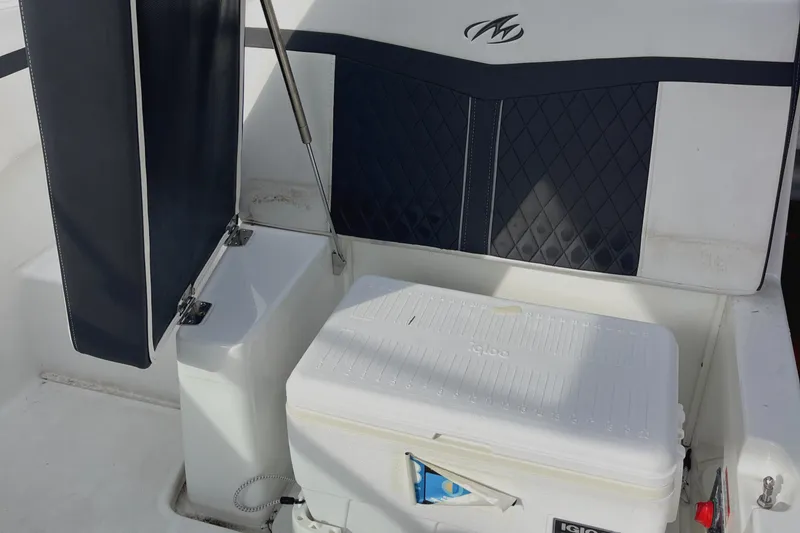 Slide: The Image of 2022 Monterey M225 boat interior with cooler and cushioned seating. - 22