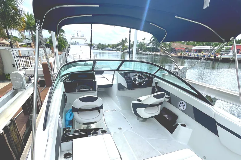 Slide: The Image of 2022 Monterey M225 boat interior with seating and steering wheel, docked by a canal. - 27