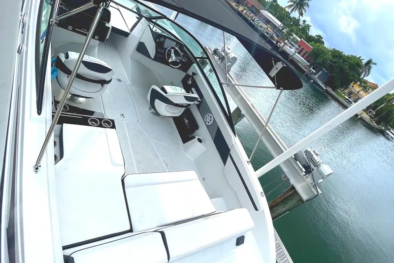 Slide: The Image of 2022 Monterey M225 boat interior with seating and steering wheel, docked by a scenic waterfront. - 28