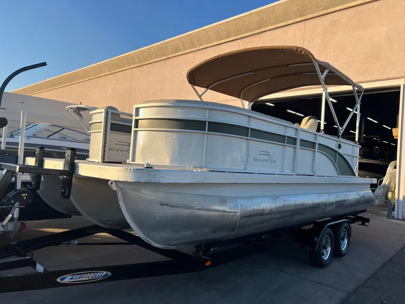 The Image of 2019 Bennington 22 SSRX pontoon boat on a trailer, parked outside a warehouse. - 1