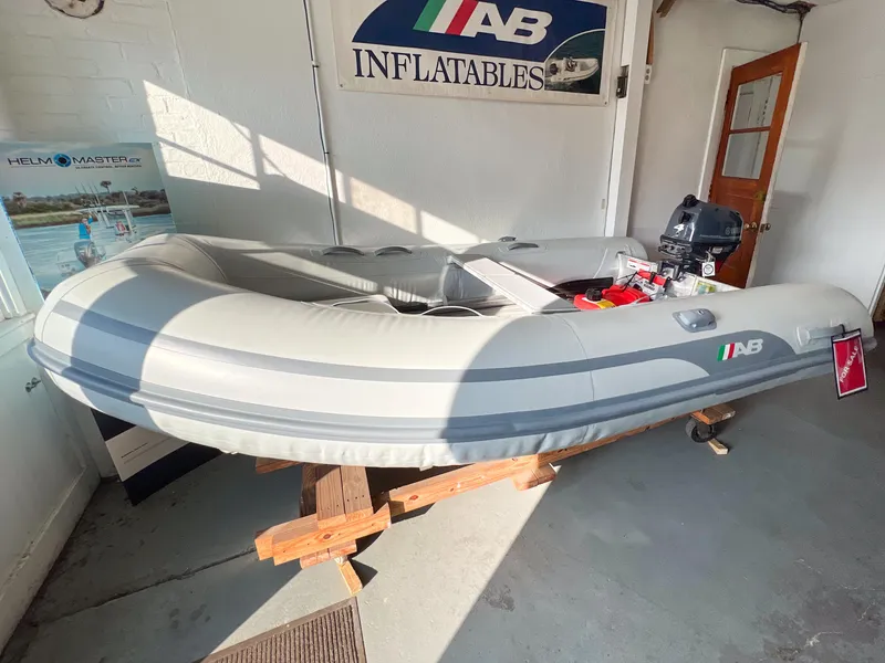 Slide: The Image of 2023 AB Inflatables 9.5 Lammina AL boat displayed indoors on wooden stands. - 4