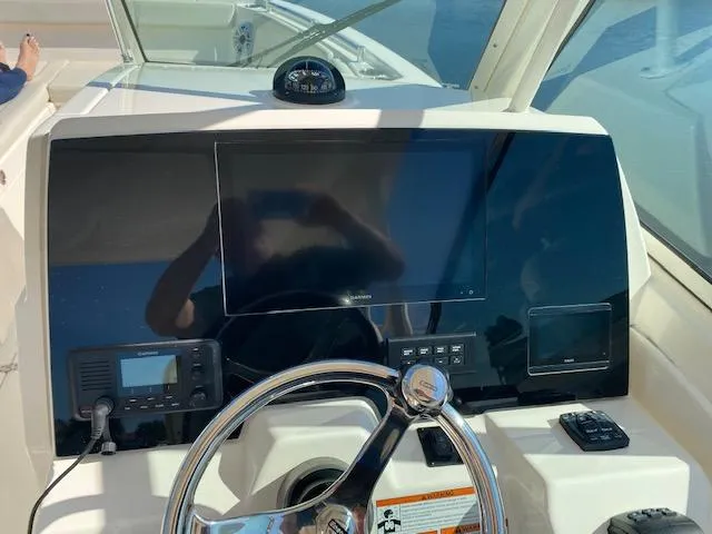 Slide: The Image of 2021 Cobia 330 Dual Console helm with steering wheel, navigation screen, and controls. - 12