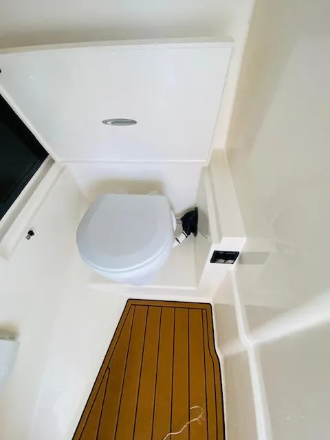 Slide: The Image of 2021 Cobia 330 Dual Console boat bathroom with wooden floor and white toilet. - 27