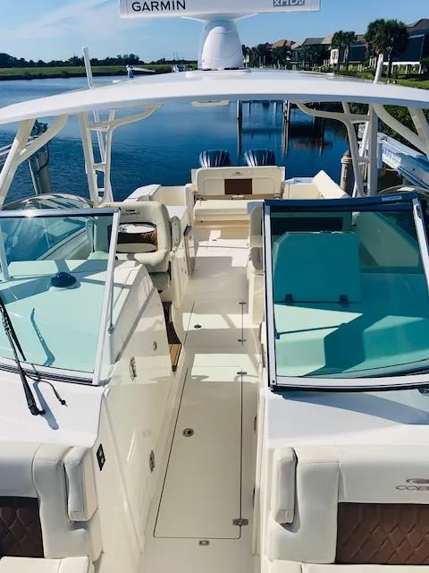 Slide: The Image of 2021 Cobia 330 Dual Console boat with open deck and seating, docked by a serene waterfront. - 33