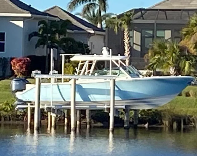 Slide: The Image of 2021 Cobia 330 Dual Console boat on lift by waterfront homes. - 4