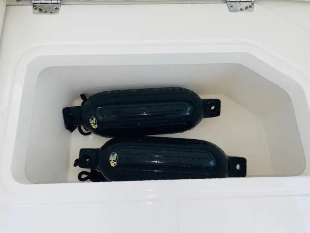 Slide: The Image of Storage compartment with black fenders on a 2021 Cobia 330 Dual Console boat. - 48